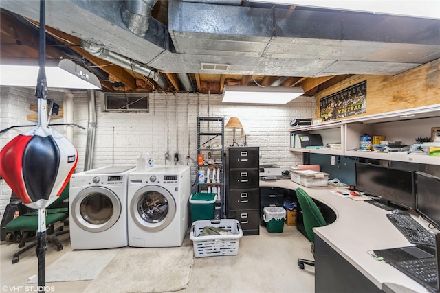 washroom with laundry area, brick wall, visible vents, and washer and clothes dryer