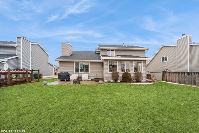 rear view of property featuring a chimney, a lawn, a patio area, and fence