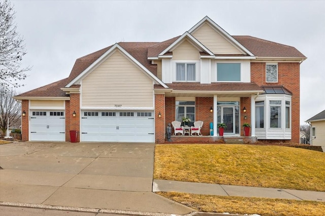 traditional home with an attached garage, a front lawn, concrete driveway, and brick siding