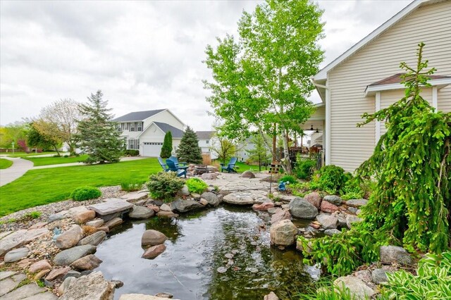 7087 Hillcrest Ct, Johnston, IA 50131 - view of grassy yard with a fire pit, a small pond, and a patio
