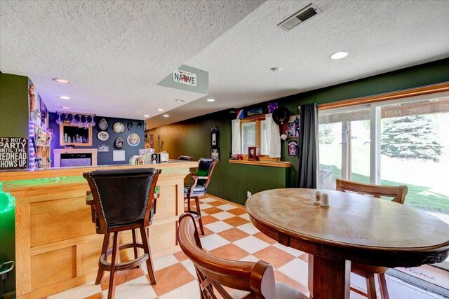 7087 Hillcrest Ct, Johnston, IA 50131 - dining room with a dry bar, a textured ceiling, light flooring, and recessed lighting