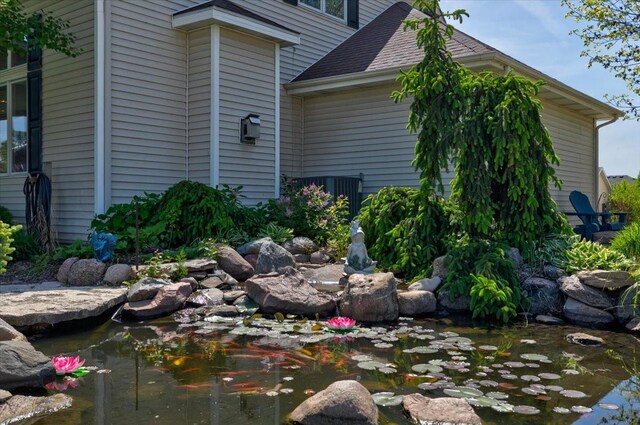 7087 Hillcrest Ct, Johnston, IA 50131 - view of property exterior with a garden pond and roof with shingles