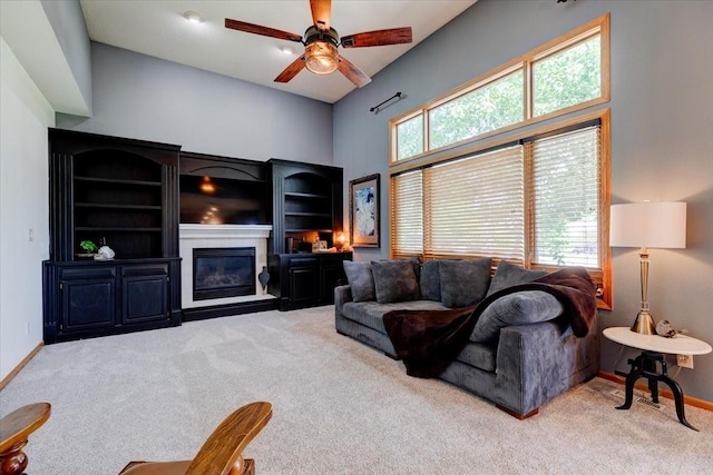 7087 Hillcrest Ct, Johnston, IA 50131 - carpeted living room with a glass covered fireplace, a towering ceiling, a ceiling fan, and baseboards