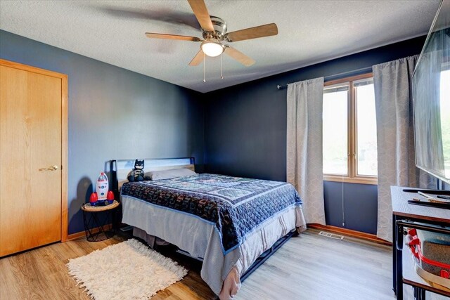 7087 Hillcrest Ct, Johnston, IA 50131 - bedroom featuring multiple windows, light wood-type flooring, a textured ceiling, a ceiling fan, and baseboards
