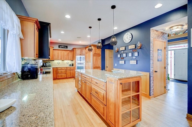 7087 Hillcrest Ct, Johnston, IA 50131 - kitchen featuring built in microwave, oven, light wood-style floors, light stone countertops, and a center island