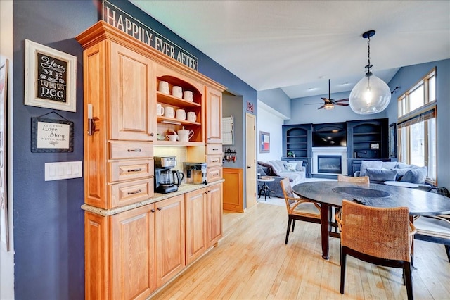 7087 Hillcrest Ct, Johnston, IA 50131 - dining area with a glass covered fireplace, a ceiling fan, and light wood-style floors