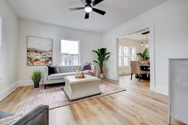 living area with ceiling fan, baseboards, and wood finished floors