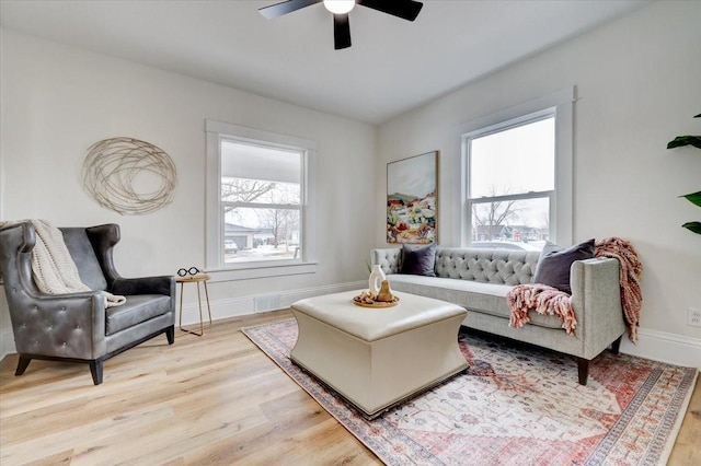 living room with light wood-type flooring, a healthy amount of sunlight, and baseboards