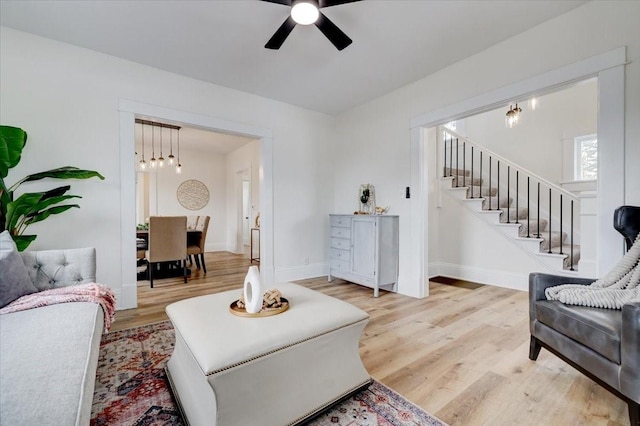 living room with ceiling fan, stairway, wood finished floors, and baseboards