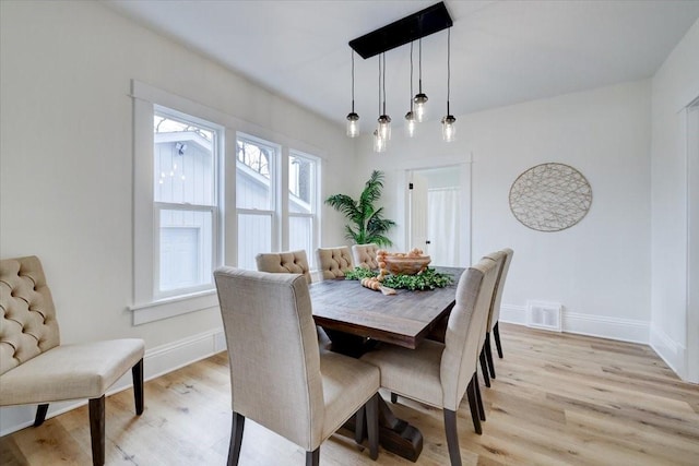 dining area with baseboards, visible vents, and light wood-style floors