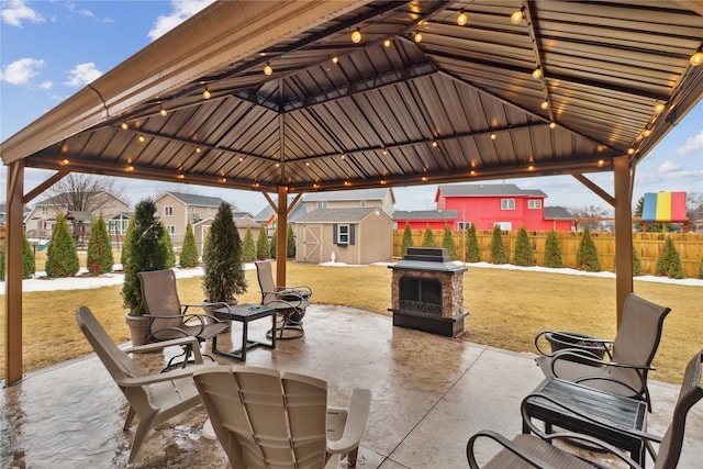 view of patio / terrace with an outbuilding, fence, a gazebo, and a storage shed