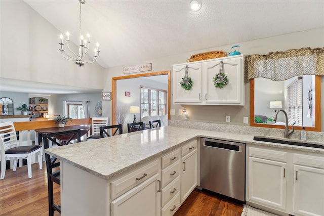 kitchen with white cabinets, vaulted ceiling, a sink, dishwasher, and a kitchen bar