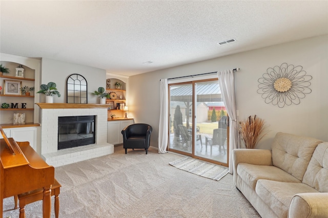 living room featuring a textured ceiling, built in shelves, light carpet, a fireplace, and visible vents