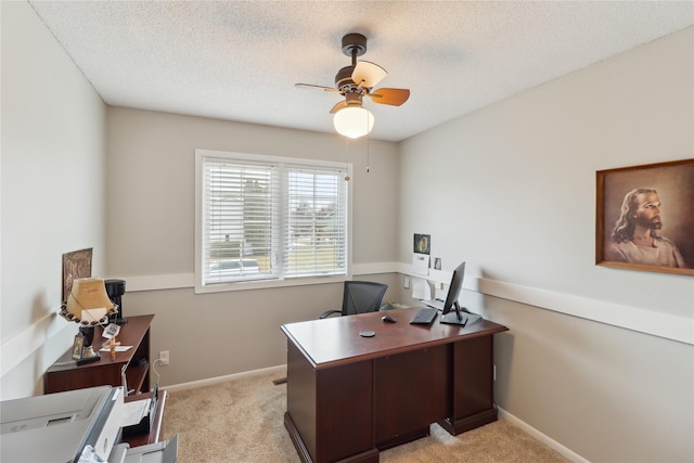 office featuring light colored carpet, ceiling fan, a textured ceiling, and baseboards