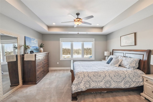 bedroom featuring a tray ceiling, recessed lighting, light colored carpet, a ceiling fan, and baseboards