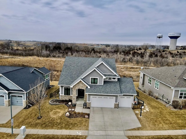 view of front of home featuring an attached garage, stone siding, concrete driveway, roof with shingles, and a front yard