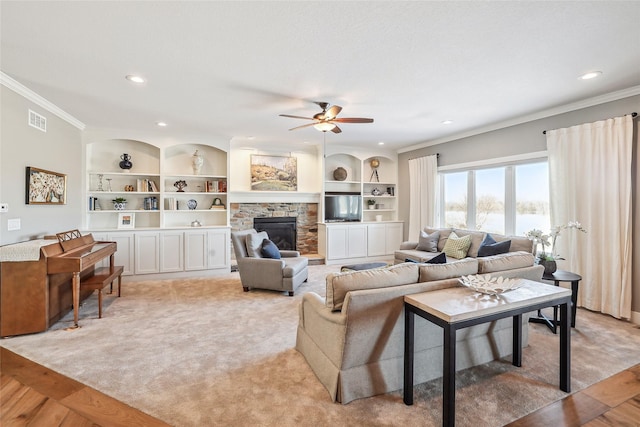 living room featuring built in shelves, visible vents, ornamental molding, light carpet, and a stone fireplace