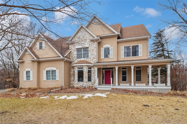 view of front of house with a porch, a front yard, stone siding, and roof with shingles