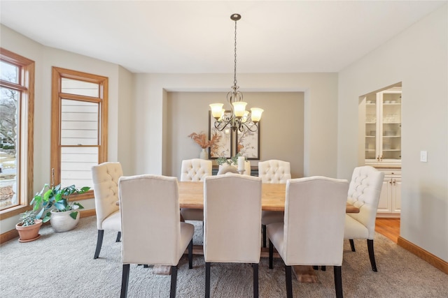 dining room with a chandelier, carpet flooring, and baseboards