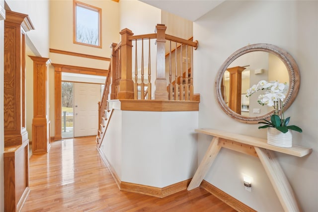 interior space with light wood finished floors, baseboards, decorative columns, and stairway