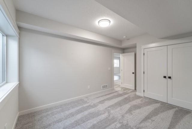 unfurnished bedroom featuring carpet floors, baseboards, visible vents, and a closet