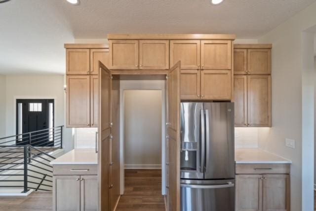 kitchen featuring light brown cabinets, light countertops, wood finished floors, and stainless steel fridge