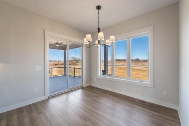 unfurnished dining area with a notable chandelier, dark wood-style flooring, visible vents, and baseboards