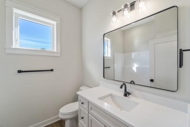 bathroom featuring toilet, wood finished floors, vanity, and baseboards