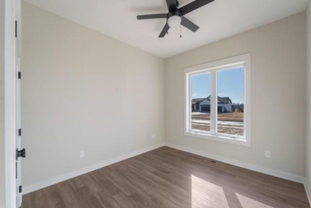 unfurnished room with ceiling fan, baseboards, and dark wood finished floors