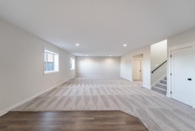 below grade area with light wood-style floors, baseboards, stairway, and recessed lighting