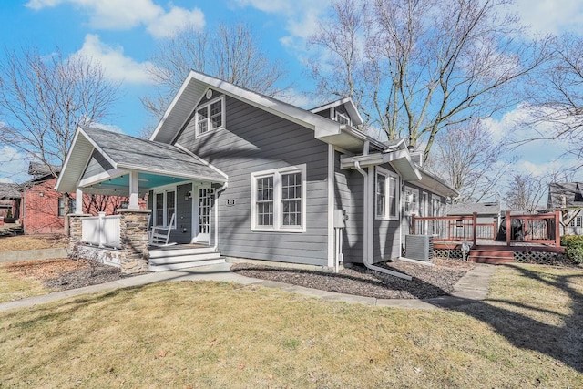 view of front of house featuring a porch, a front yard, and central AC