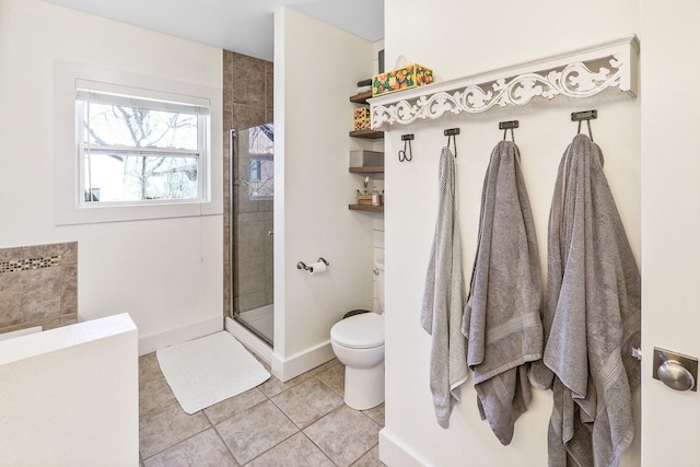 bathroom with tiled shower, tile patterned flooring, toilet, and baseboards