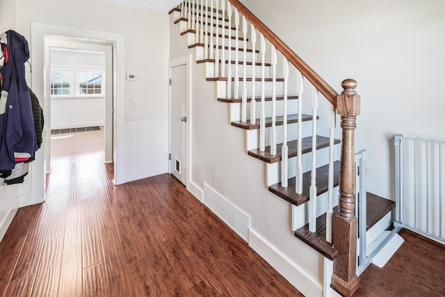 staircase with radiator, wainscoting, visible vents, and wood finished floors