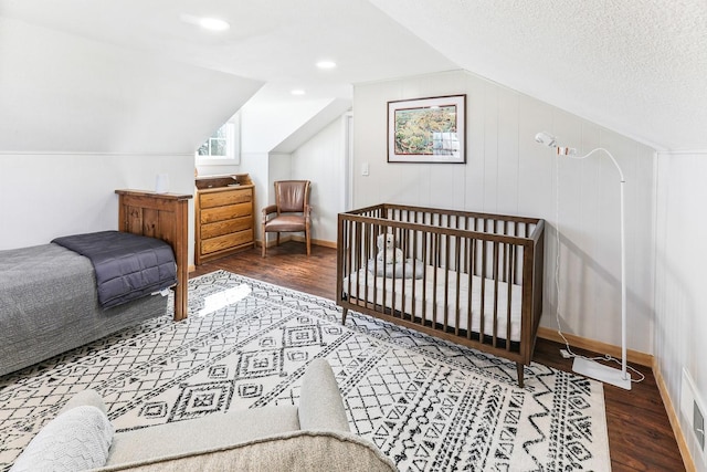 bedroom with lofted ceiling, a textured ceiling, wood finished floors, and baseboards