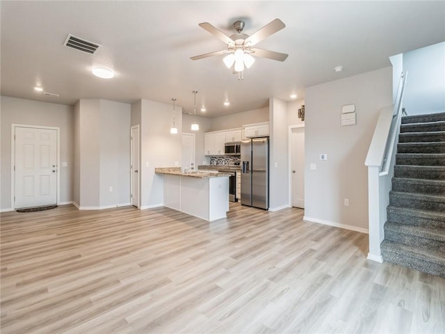 kitchen featuring stainless steel appliances, open floor plan, a peninsula, and white cabinets