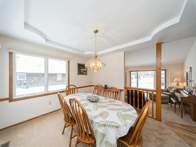 dining area with a tray ceiling, baseboards, visible vents, and an inviting chandelier