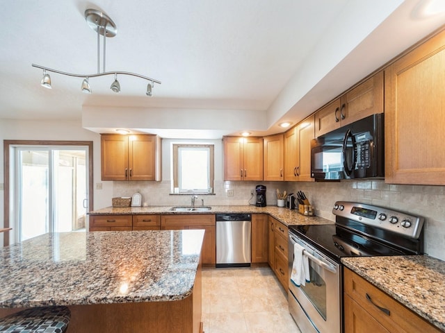 kitchen featuring a sink, light stone counters, backsplash, stainless steel appliances, and brown cabinetry