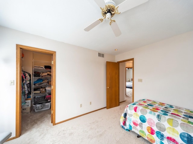 bedroom featuring visible vents, baseboards, a closet, a walk in closet, and light colored carpet