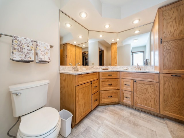 bathroom featuring a sink, toilet, recessed lighting, and double vanity