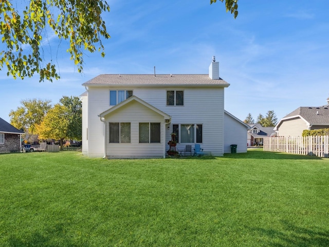 back of house featuring a chimney, a yard, and fence