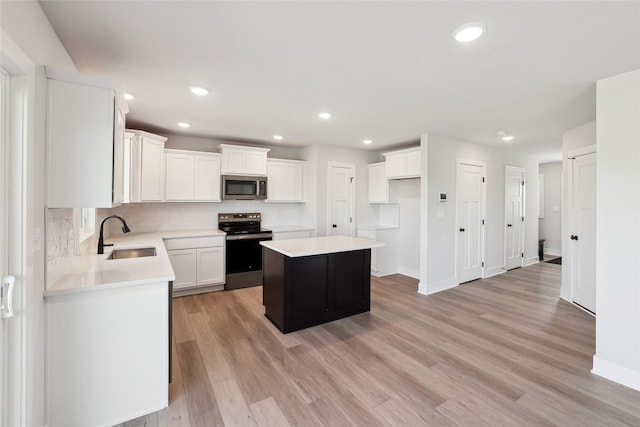 2208 White Oak Ln, Granger, IA 50109 - kitchen with appliances with stainless steel finishes, a sink, a kitchen island, backsplash, and light wood-type flooring