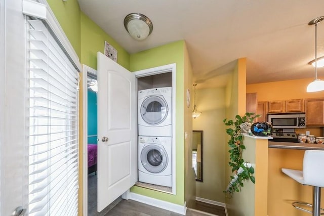 clothes washing area featuring laundry area, stacked washer / dryer, and baseboards