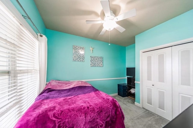 carpeted bedroom with a ceiling fan, a closet, and baseboards