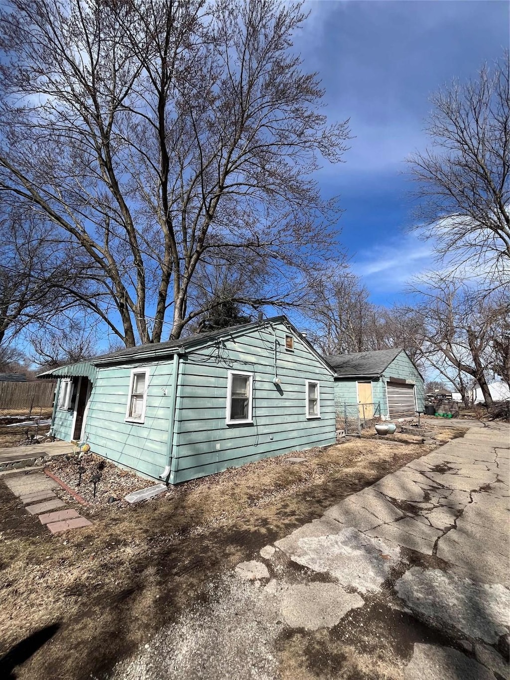 view of side of home featuring a detached garage, driveway, and fence