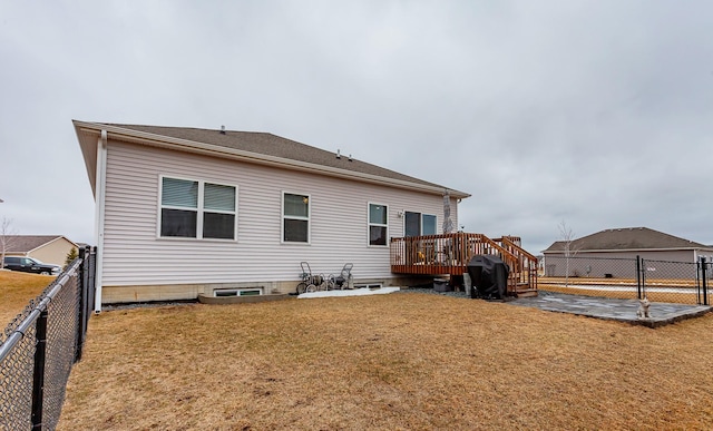 back of property featuring a wooden deck, a lawn, and a fenced backyard