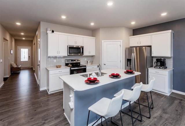 kitchen featuring a breakfast bar area, light countertops, appliances with stainless steel finishes, dark wood-style floors, and a sink