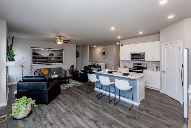 kitchen featuring white cabinets, dark wood-style floors, open floor plan, and stainless steel appliances