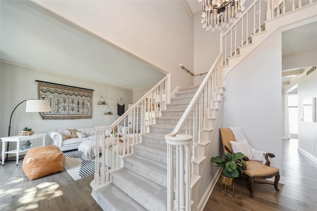 staircase featuring an inviting chandelier, wood finished floors, and crown molding