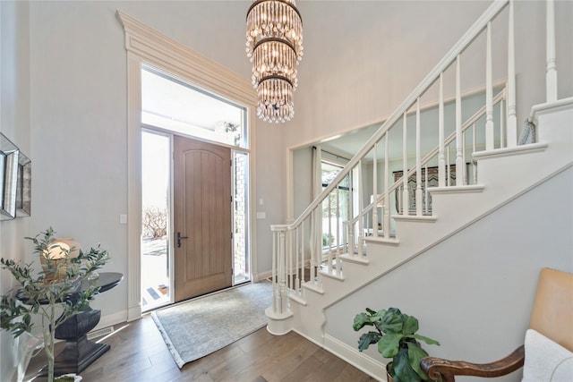 foyer entrance featuring baseboards, stairs, an inviting chandelier, and hardwood / wood-style floors