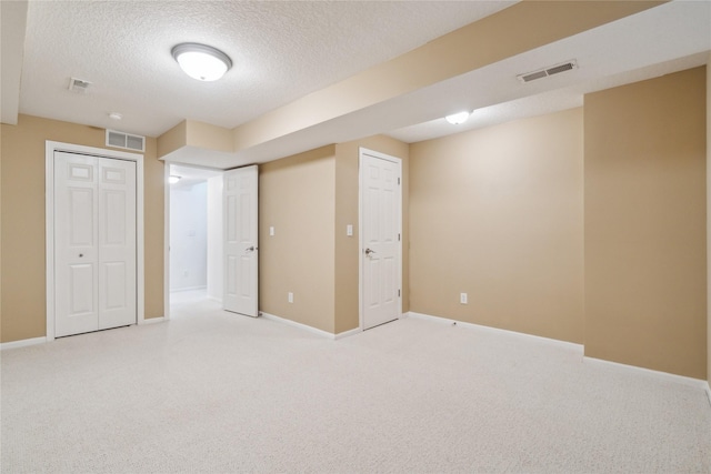 interior space featuring baseboards, light colored carpet, visible vents, and a textured ceiling